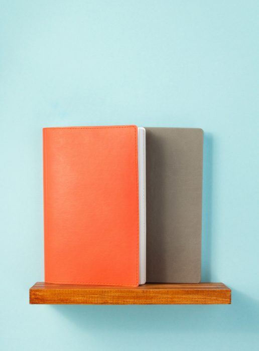 notepad and book on shelf at wall background